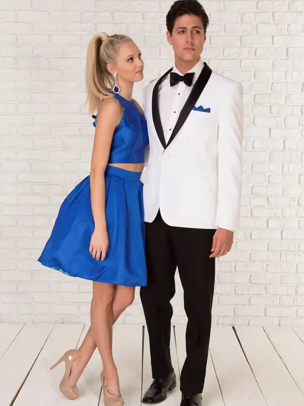 Man in a Clayton white jacket with black trim and a woman in a blue top and short skirt