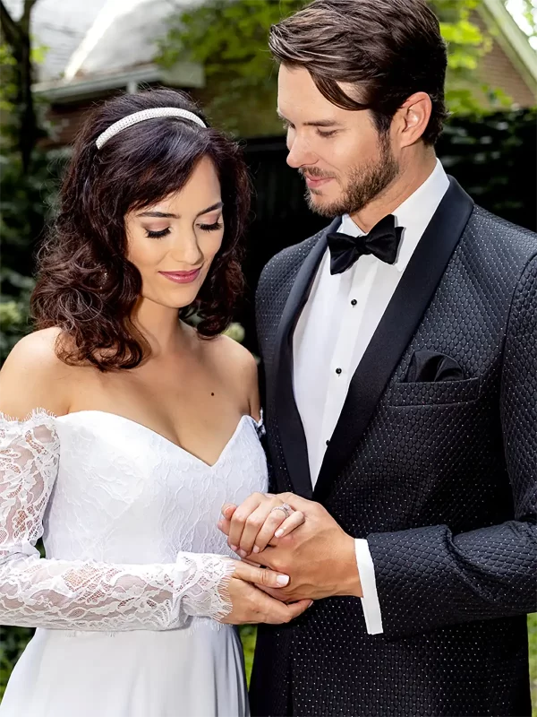 Man in a black diamond weave jacket and with a woman in a white bride's dress